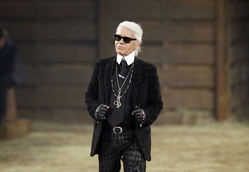 In this Tuesday, Dec. 10, 2013, file photo, Chanel designer Karl Lagerfeld takes a bow at the end of his Metiers d'Art fashion show, Tuesday, Dec. 10, 2013, in Dallas. Chanel's iconic couturier, Karl Lagerfeld, whose accomplished designs as well as trademark white ponytail, high starched collars and dark enigmatic glasses dominated high fashion for the last 50 years, has died. He was around 85 years old. (AP Photo/Tony Gutierrez, File)