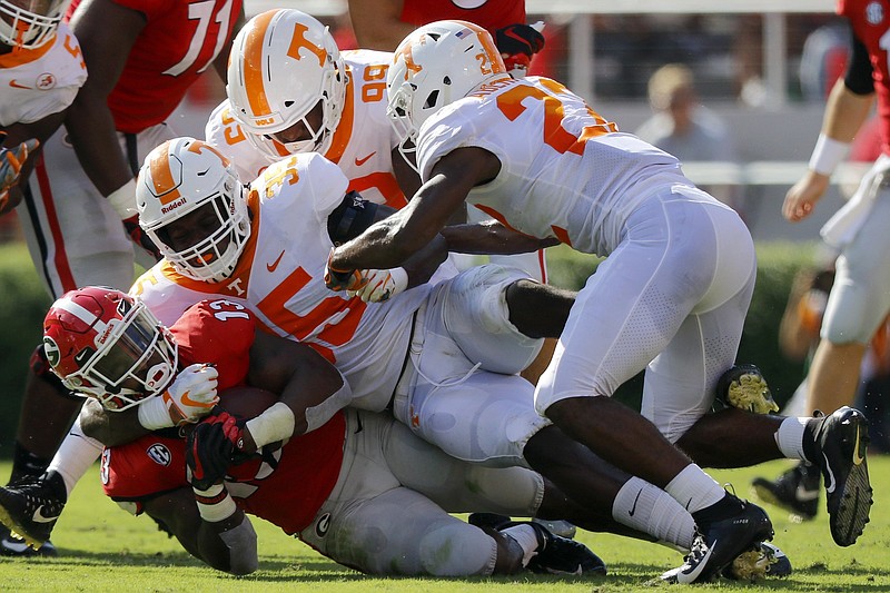 Georgia running back Elijah Holyfield is tackled by Tennessee linebacker Daniel Bituli last September in Athens. Georgia rivals Auburn and Tennessee are essentially swapping spots on the Bulldogs' schedule starting in 2020.