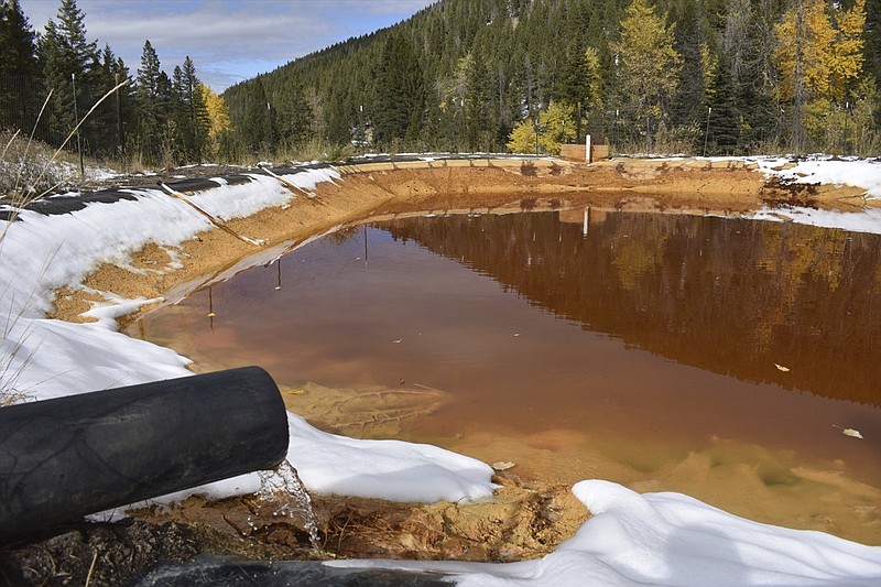 In this Oct. 12, 2018, photo, water contaminated with arsenic, lead and zinc flows from a pipe out of the Lee Mountain mine and into a holding pond near Rimini, Mont. The community is part of the Upper Tenmile Creek Superfund site, where dozens of abandoned mines have left water supplies polluted and residents must use bottled water. (AP Photo/Matthew Brown)