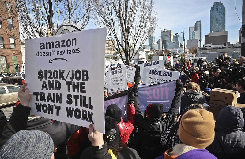 In this Nov. 14, 2018, file photo, protesters carry anti-Amazon posters during a coalition rally and news conference opposing Amazon headquarters.