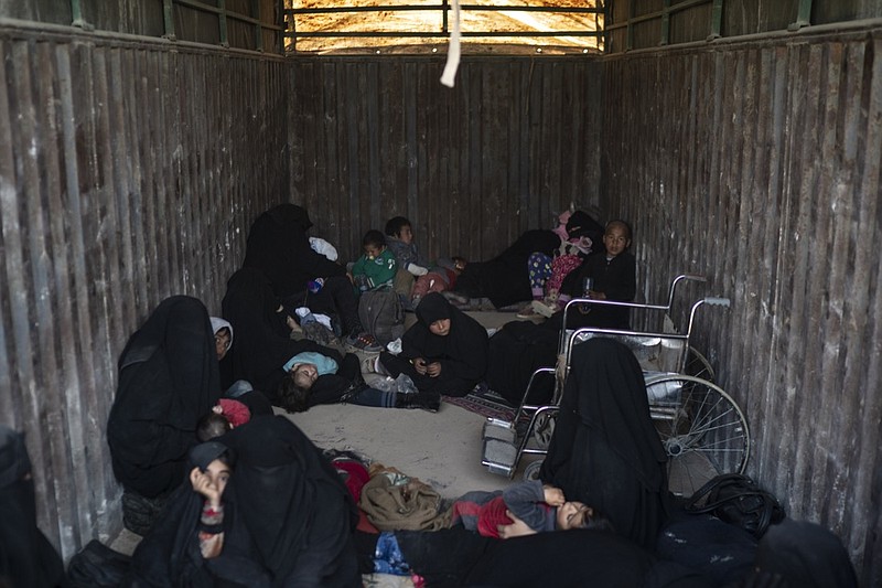 Women and children ride in the back of a truck that is part of a convoy evacuating hundreds out of the last territory held by Islamic State militants in Baghouz, eastern Syria, Wednesday, Feb. 20, 2019. The evacuation signals the end of a week long standoff and opens the way to U.S.-backed Syrian Democratic Forces (SDF) recapture the territory. (AP Photo/Felipe Dana)
