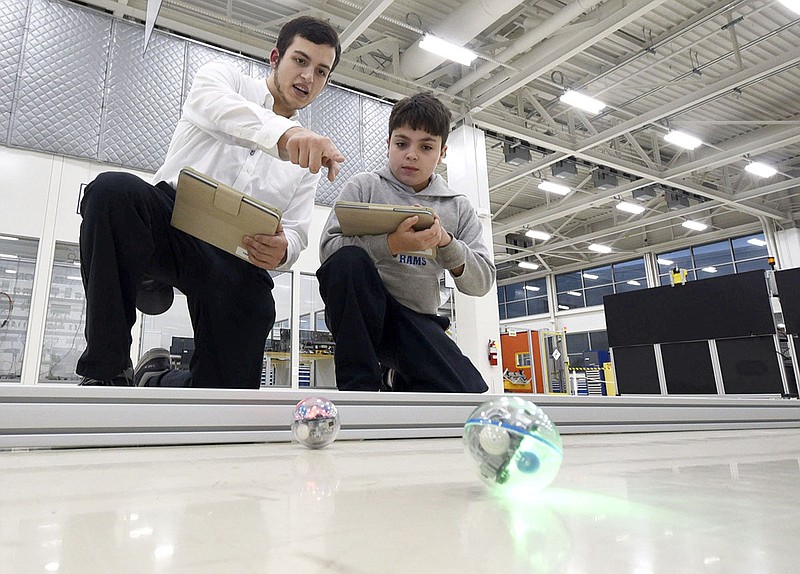 Mechatronics Akademie AMP 10 student Justin Douglass, left, instructs OLPH student Cooper Ebberly, 11, with basic robotic commands via blue tooth on an iPad Thursday night, Feb. 21, 2019, at Volkswagen Academy. / Staff photo by Tim Barber