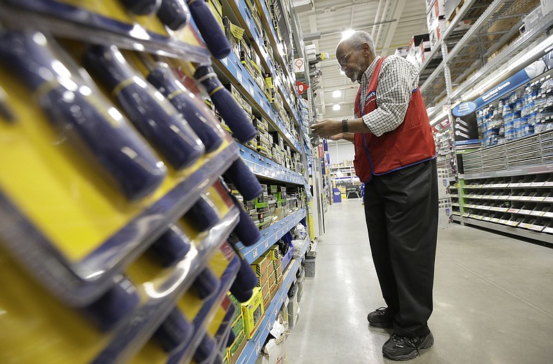 FILE- In this Feb. 23, 2018, file photo sales associate Larry Wardford, of Holliston, Mass., places items on selves at a Lowe's retail home improvement and appliance store, in Framingham, Mass. Lowe's Companies, Inc. reports financial results Wednesday, Feb. 27, 2019. (AP Photo/Steven Senne)