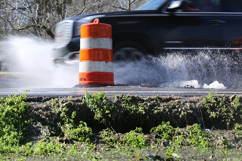 Water splashes up as a car drives through the roadway where water is pouring out of a manhole cover in the 2900 block of Hamill Road Sunday, February 24, 2019 in Hixson, Tennessee. Chattanooga Police Officer Nicholas Galinger was struck in a hit-and-run while he was out of the patrol car inspecting the manhole cover late Saturday night, and he later succumbed to injuries sustained in the hit-and-run.