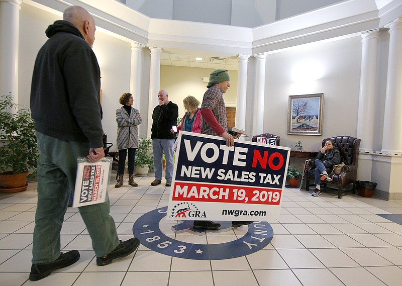 Staff photo by Erin O. Smith / Eric Morrison walks into the Catoosa County Administration Building with a large sign in protest of a sales tax increase Tuesday, February 19, 2019 in Ringgold, Georgia. A group of about 10 individuals showed up to the Catoosa County Commission meeting Tuesday to voice their objection to the additional 1-percent tax increase saying it would put an extra burden on those in the community couldn't afford it, would encourage people to shop online where sales tax may not be required or cause locals to go out of town to shop.