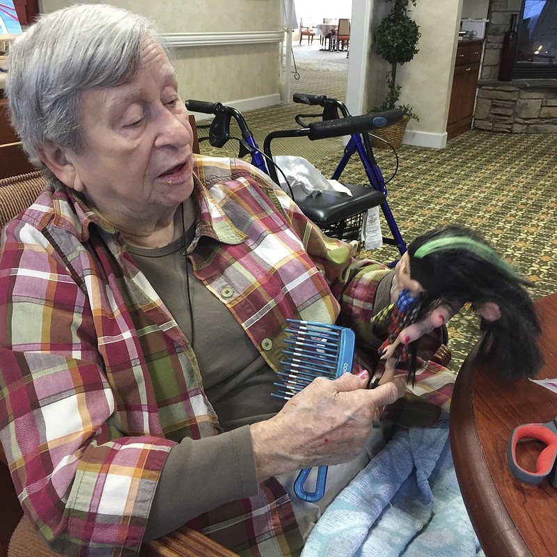 Peggy McCallie, 81, a resident of Morning Point Assisted Living Residence in Ooltewah, grooms a doll for resale at the Samaritan Center. 