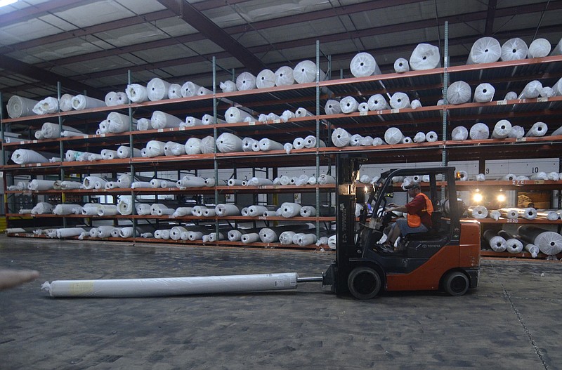 In this 2013 staff file photo, Johnny Grissom moves a roll of carpet Friday at the Dixie Group in North Georgia.