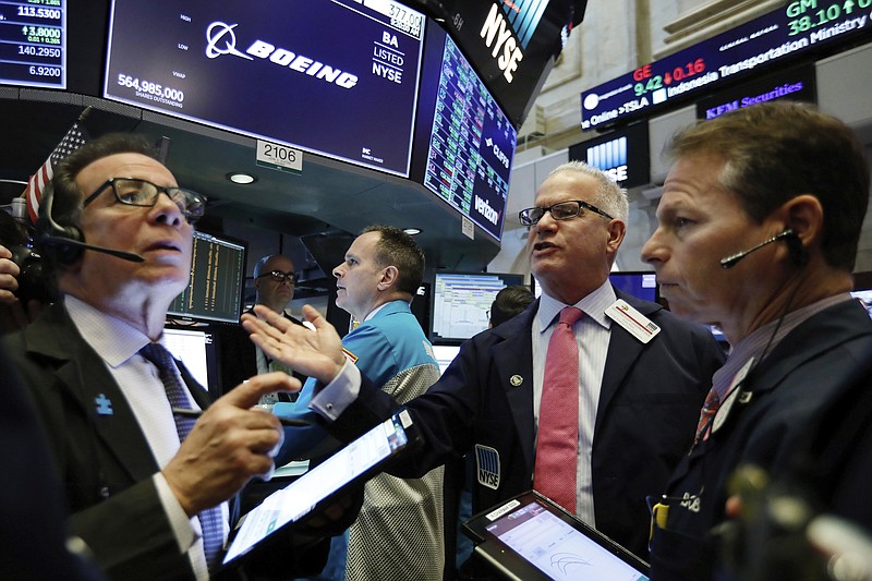 FILE- In this March 11, 2019, file photo NYSE Floor Governor Rudy Mass, second from right, works with traders at the post that handles Boeing, on the floor of the New York Stock Exchange. Boeing soared early in 2019 and lifted the Dow Jones Industrial Average with it. Now concerns about the safety of the newest version of its flagship airplane have halted the momentum. (AP Photo/Richard Drew, File)