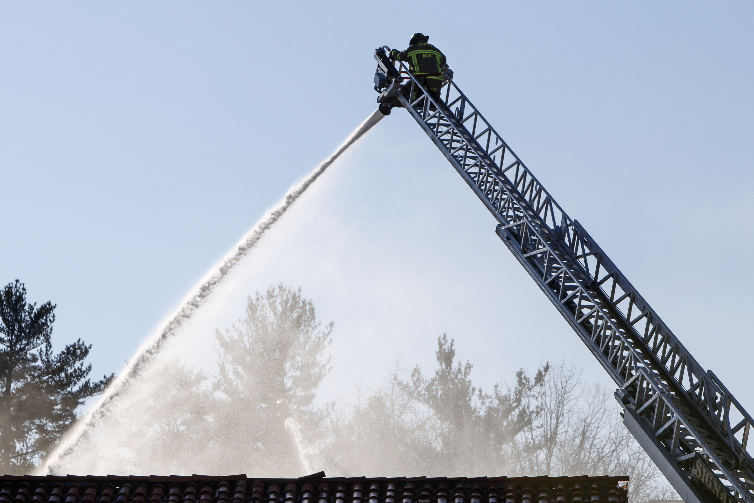 A firefighter works from the top of a ladder while working to put out a fire at Patron Mexican Grill located at 3720 Taft Highway on Monday, March 18, 2019 in Signal Mountain, Tenn.