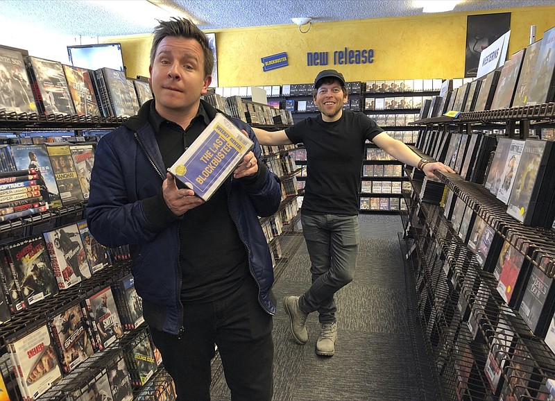 Local documentary filmmakers Taylor Morden, left, and Zeke Kamm, pose at the last Blockbuster on the planet in Bend, Ore., on Monday, March 11, 2019, with a promotional VHS tape of their upcoming documentary about the store titled The Last Blockbuster. When a Blockbuster in Perth, Australia, shuts its doors for the last time on March 31, the store in Bend, Ore., will be the only one left on Earth, and most likely in the universe. (AP Photo/Gillian Flaccus)