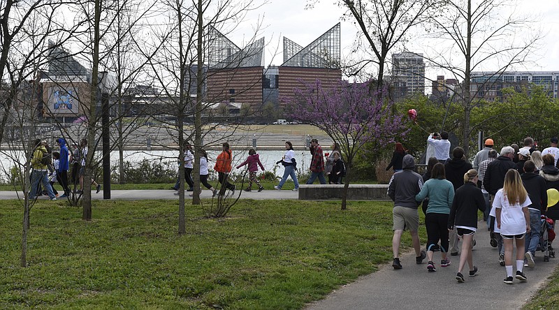 With the Tennessee Aquarium seen across the river, a group of walkers pass through Renaissance Park during the Strides of March event Sunday, Mar. 20, 2016, in Chattanooga, Tenn. The purpose of the annual event is to raise awareness of HIV and AIDS and to raise money for Chattanooga Cares. 