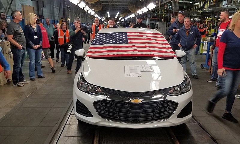 An American flag drapes the hood of the last Chevrolet Cruze as it comes off the assembly line at a General Motors plant where 1,700 hourly positions are being eliminated perhaps for good, on Wednesday, March 6, 2019, in Lordstown, Ohio. The factory near Youngstown is the first of five North American auto plants that GM plans to shut down by next year. (Tim O'Hara via AP)