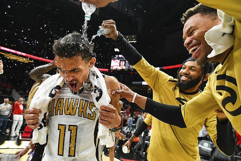 Atlanta Hawks rookie point guard Trae Young is doused by teammates Justin Anderson, right, and DeAndre' Bembry as they celebrate Young's winning basket in the final moments of Saturday night's home game against the Philadelphia 76ers.