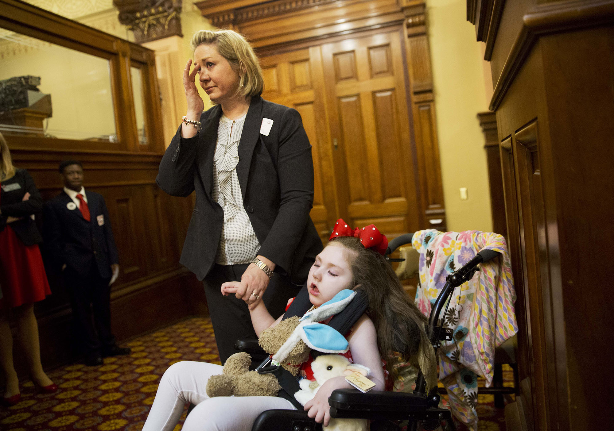 Janea Cox, whose daughter Haleigh, 5, right, suffers seizures, wipes a tear while waiting for the House to vote on