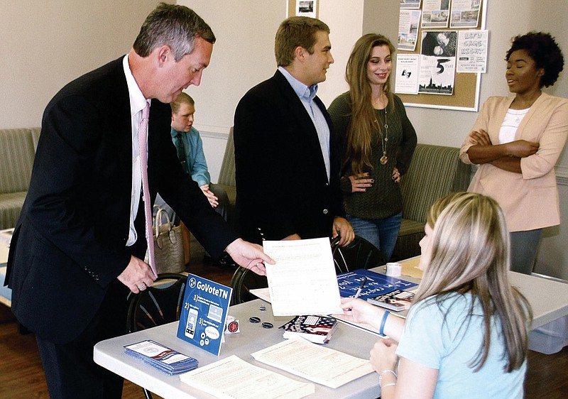 In this Sept. 29, 2016, file photo, Tennessee Secretary of State Tre Hargett helps Ami Burchfield with voter registration paperwork at Maryville College helping students register to vote, in Maryville, Tenn. Amid growing national concerns about election security, Tennessee's three largest counties are moving toward voting machines that produce a voter-verifiable paper trail for the presidential primaries in 2020. Hargett says he's letting counties decide whether to switch. (The Daily Times via AP, File)