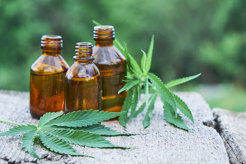 hemp leaves on wooden background, seeds, cannabis oil extracts in jars. cbd tile / Getty Images