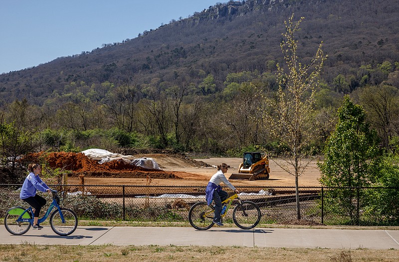 Cyclists ride past construction clearing way for an Alton Park connector trail from the Wheeland Foundry Trailhead of the Tennessee Riverwalk on Wednesday, March 27, 2019, in Chattanooga, Tenn. Officials are looking at ways to expand the riverwalk onto the North Shore, into St. Elmo and onto Lookout Mountain.