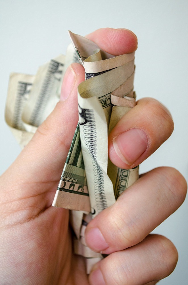 Crumpled 5 dollar bills in a hand. money tile pay tile pay gap wage gap / Getty Images