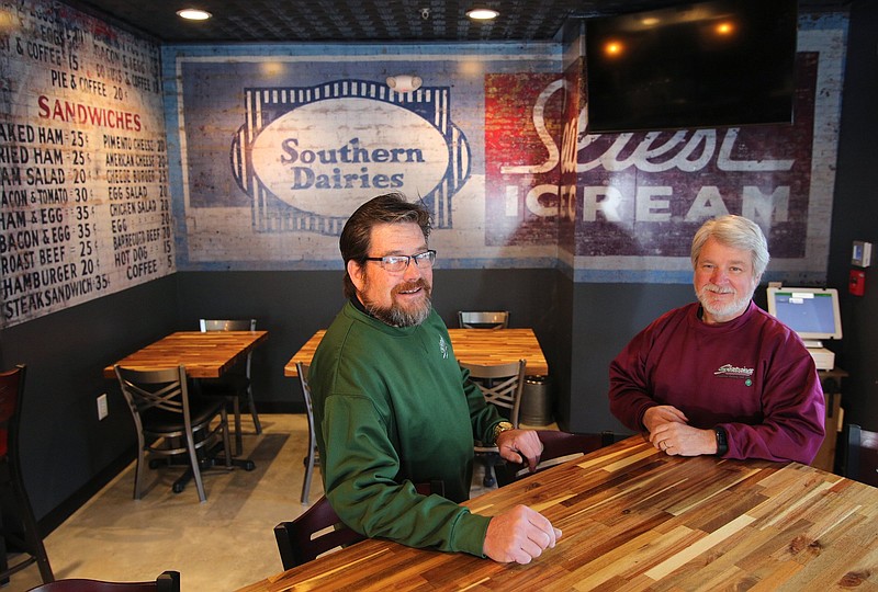 Staff photo by Erin O. Smith / Steve Flynn and Kerry Hoefer, co-owners of Stevarino's, sit in their new restaurant on the North Shore in front of a reproduction of an old wall advertisement. The location will be the third Stevarino's with the others in South Pittsburg, Tennessee, and in Scottsboro, Alabama.