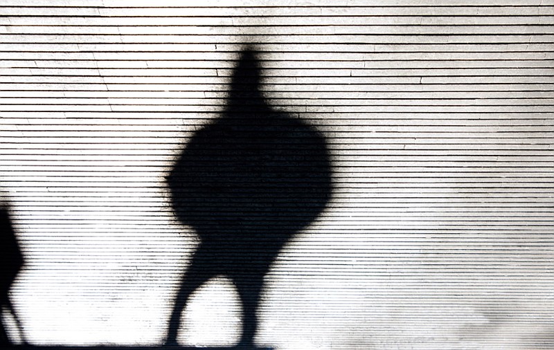 Blurry crooked shadow silhouette of a person walking city street patterned sidewalk in black and white illegal immigration tile migrant border tile / Getty Images