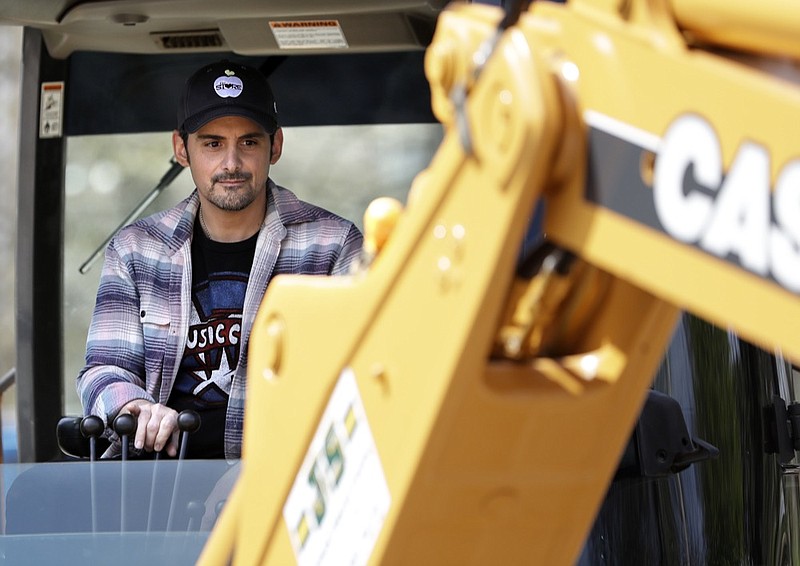 Country music star Brad Paisley operates a backhoe as he breaks ground for The Store, a free grocery store for people in need, Wednesday, April 3, 2019, in Nashville, Tenn. (AP Photo/Mark Humphrey)

