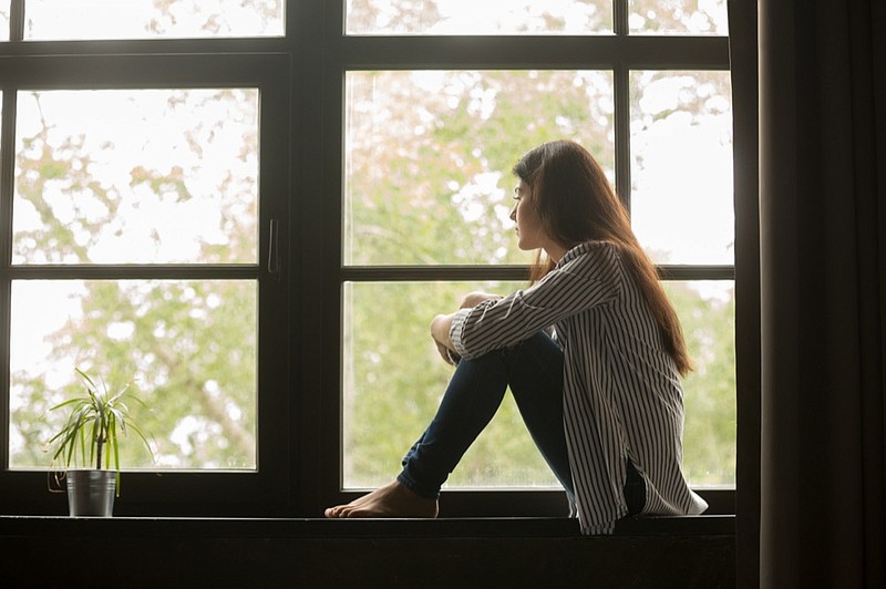 Thoughtful girl sitting on sill embracing knees looking at window, sad depressed teenager spending time alone at home, young upset pensive woman feeling lonely or frustrated thinking about problems lonely tile loneliness tile / Getty Images