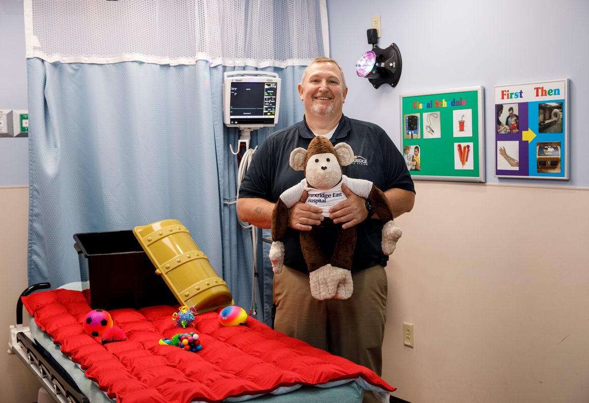 Director of Emergency Services Dale Solomon holds a weighted monkey as he poses for a portrait in a new sensory-friendly exam room in the emergency room at Parkridge East on Thursday, April 4, 2019, in Chattanooga, Tenn. The room includes special features like sound-proofing, calming lighting and a weighted blanket to accommodate patients with autism and sensory sensitivity.