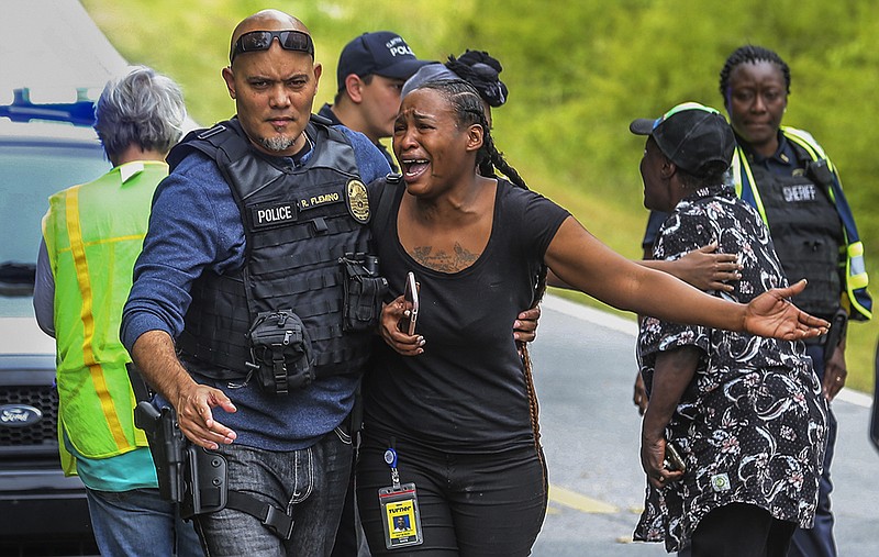 A woman believed to be related to ones involved in a hostage situation reacts as law enforcement on the scene tried to console them in Stockbridge, Ga., Thursday, April 4, 2019. A gunman suspected of shooting two Georgia police officers remain barricaded in a home Thursday with a teenager who was considered a hostage, police said. (John Spink/Atlanta Journal-Constitution via AP)

