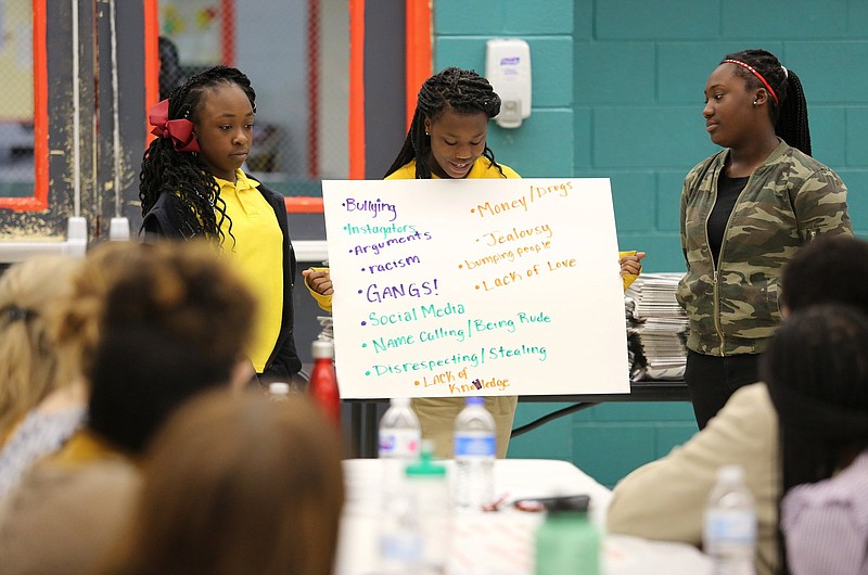 Curing Brown, 13, Jaliyah Melvin-Johnson, 13, and Tommyuanna Johnson, 13, present the ideas they came up with for what fuels gun violence at the Cost of the Crossfire forum hosted by the Chattanooga Times Free Press Wednesday, April 10, 2019 at the Carver Youth and Family Development Center in Chattanooga, Tennessee. Some of their ideas included bullying, racism, social media, lack of love and jealousy among other things.