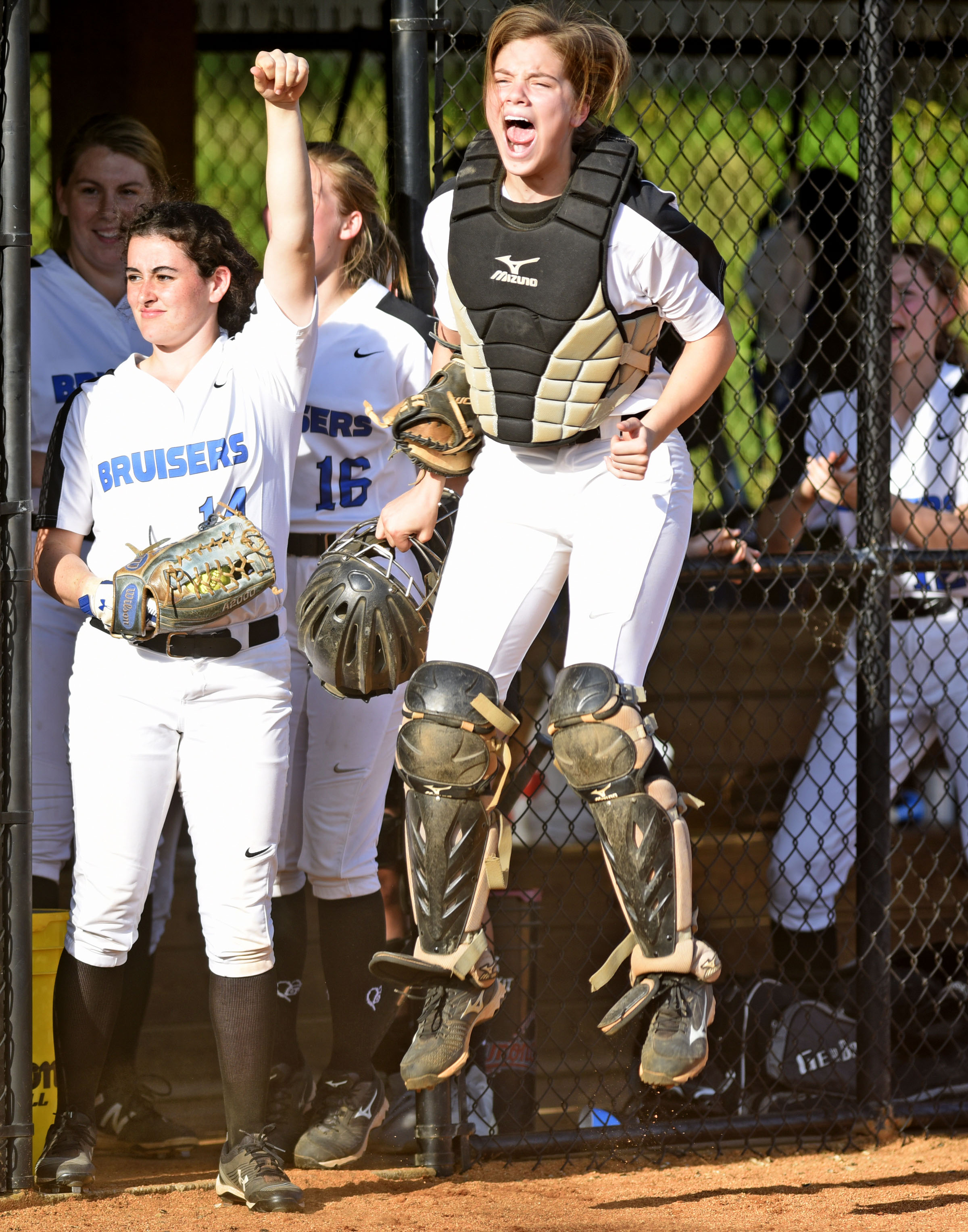 GPS catcher Ansley Blevins leaps as she celebrates teammate Brynley Oliver's score against visiting Baylor on Thursday. Also celebrating are Elizabeth Warwick (14) and the rest of the Bruisers, who beat Baylor 5-0. Blevins hit a grand slam earlier in the game.