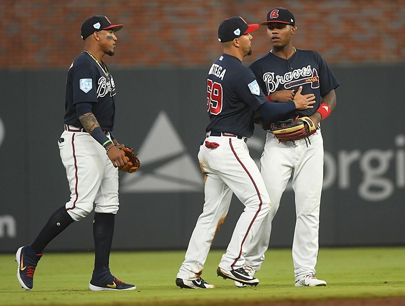 From left, the Atlanta Braves' Johan Camargo, Rafael Ortega and Cristian Pache celebrate after an exhibition baseball game against the Cincinnati Reds on March 25 in Atlanta.