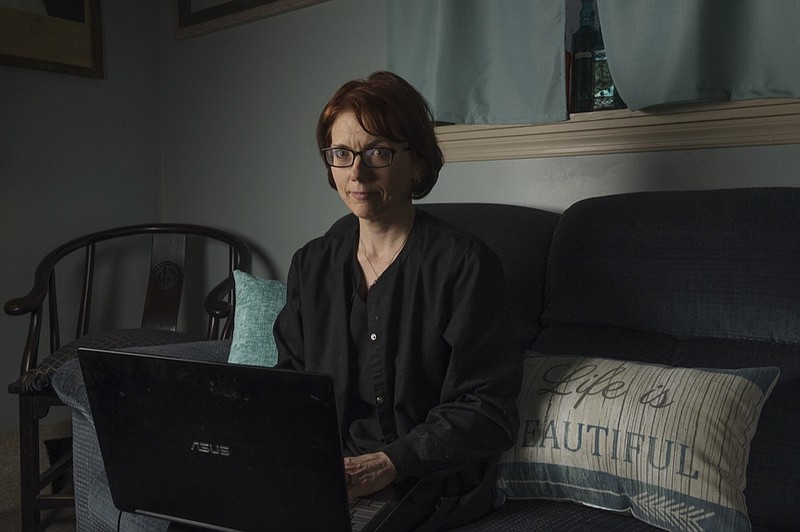 In this Friday, April 5, 2019, photo, Kelly Povroznik poses for a portrait inside the living room of her home in Weston, W.Va. Povroznik teaches an online college course that has been hampered by slow connections on her computer and phone. There is widespread agreement that expanding broadband internet in rural America is desperately needed. (AP Photo/Craig Hudson)

