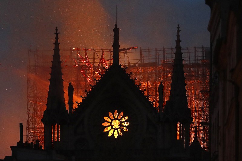 Flames and smoke rise from Notre Dame cathedral as it burns in Paris, Monday, April 15, 2019. Massive plumes of yellow brown smoke is filling the air above Notre Dame Cathedral and ash is falling on tourists and others around the island that marks the center of Paris. (AP Photo/Thibault Camus)