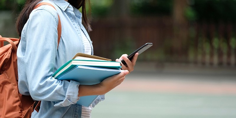 
Student girl holding books and smartphone while walking in school campus background, education, back to school concept college campus books study / Getty Images