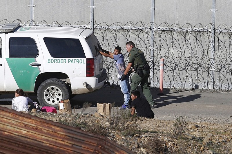FILE - In this Dec. 15, 2018, file photo, Honduran asylum seekers are taken into custody by U.S. Border Patrol agents after the group crossed the U.S. border wall into San Diego, Calif., seen from Tijuana, Mexico. Detained asylum seekers who have shown they have a credible fear of returning to their country will no longer be able to ask a judge to grant them bond. U.S. Attorney General William Barr decided Tuesday, April 16, 2019, that asylum seekers who clear a "credible fear" interview and are facing removal don't have the right to be released on bond while their cases are pending and will have to wait in detention until their case is adjudicated. (AP Photo/Moises Castillo, File)

