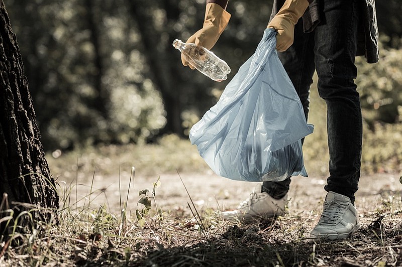 
Gathering bottles. Young pupil wearing dark jeans and white sneakers gathering empty bottles in the forest trash tile litter tile / Getty Images