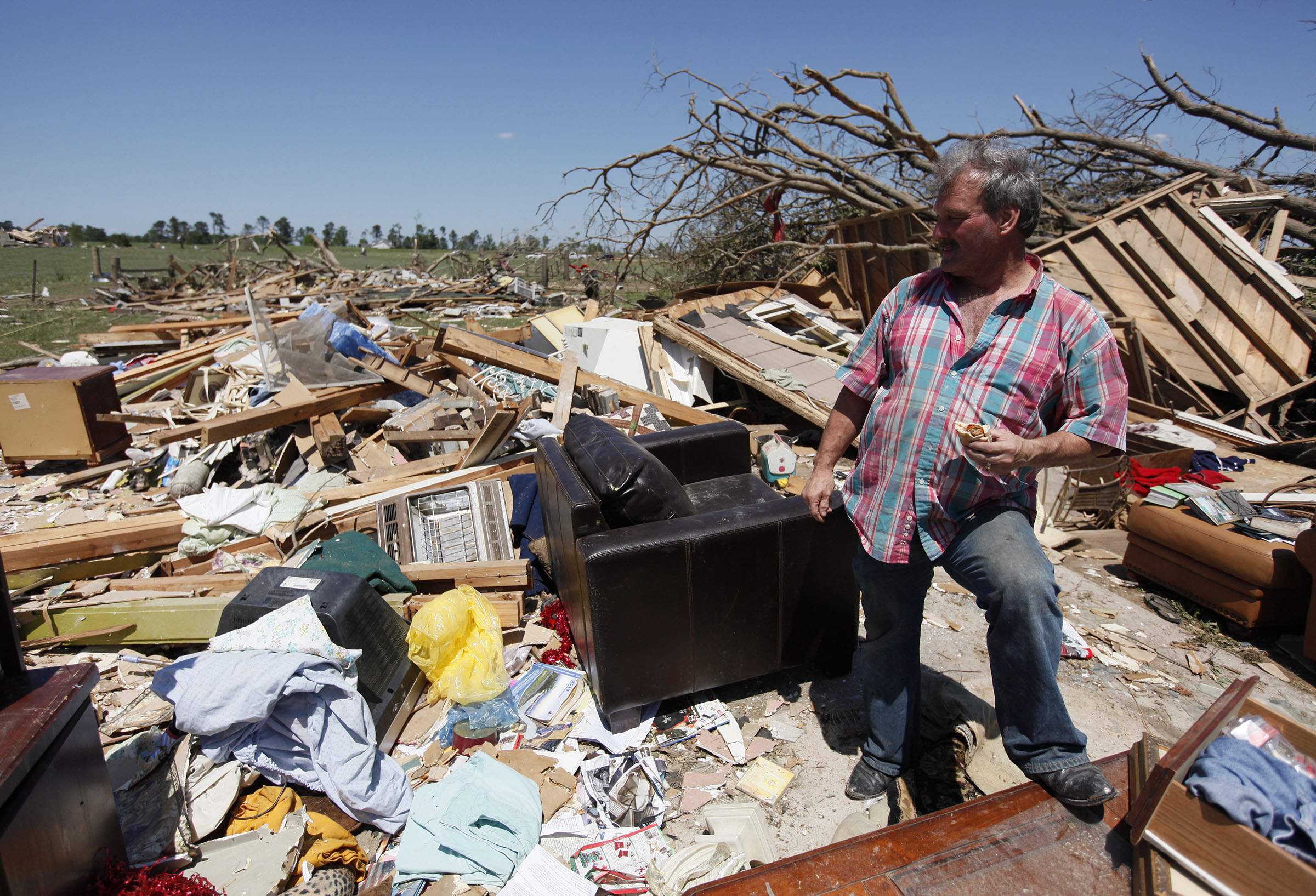 Staff Photo by Dan Henry/Chattanooga Times Free Press - March 29, 2011 - Ray Cardin eats a sandwich while standing in the spot where he survived a tornado huddled with his fiancee and dog in the center of their Rainsville, AL., residence.