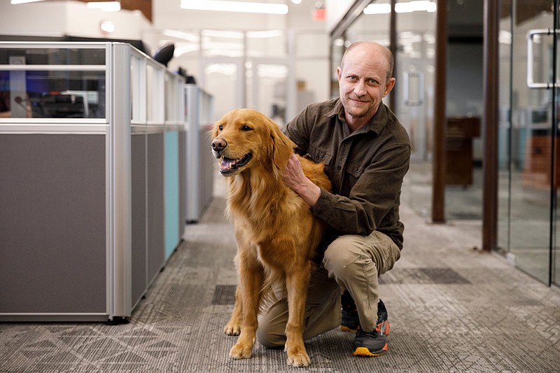 John Woody pets LeBron, the office dog and chief happiness officer, at Lync Logistics.