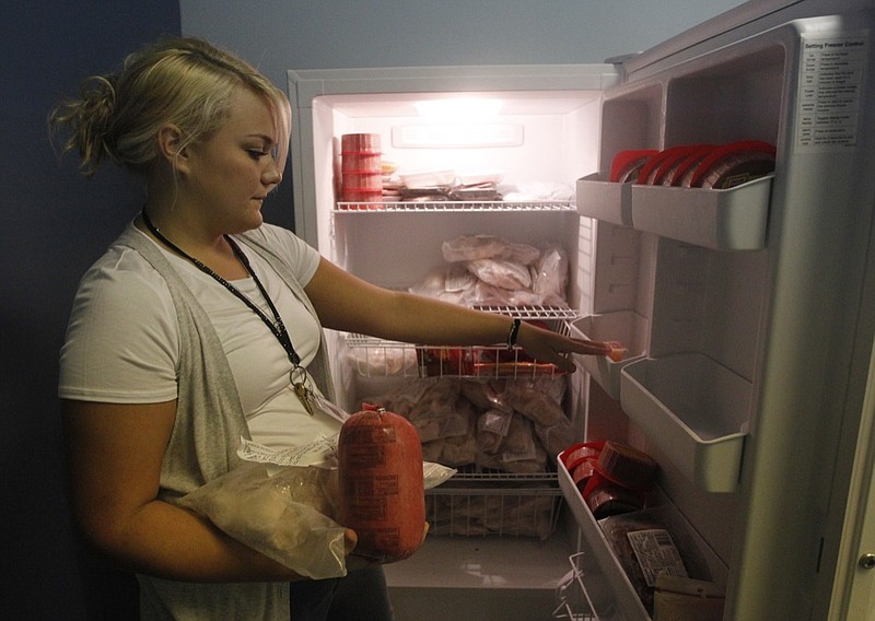 Geriatrics case manager Kristin Meador takes frozen meats from a freezer to be packed for delivery to a client Friday, Oct. 4, 2013, at Partnership Elder Services in Eastgate Town Center in Chattanooga, Tenn. 