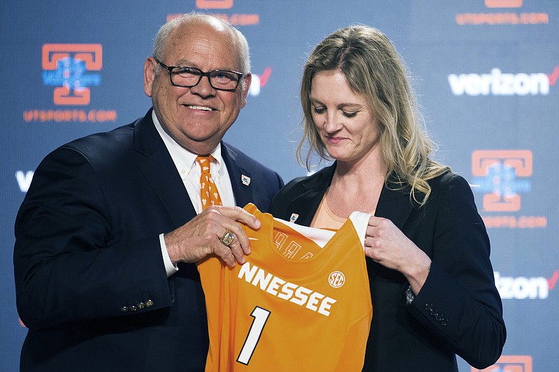 University of Tennessee athletic director Phillip Fulmer passes a jersey to Kellie Harper during a press conference announcing her as the new head coach of the Lady Vols, in the Ray and Lucy Hand Studio on University of Tennessee's campus Wednesday, April 10, 2019 in Knoxville, Tenn. (Caitie McMekin/Knoxville News Sentinel via AP)