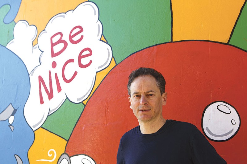 Jeffrey Cross, shown in front of a mural on the side of the Studio Eleven building in St. Elmo, started the community's email listserv in 2002.