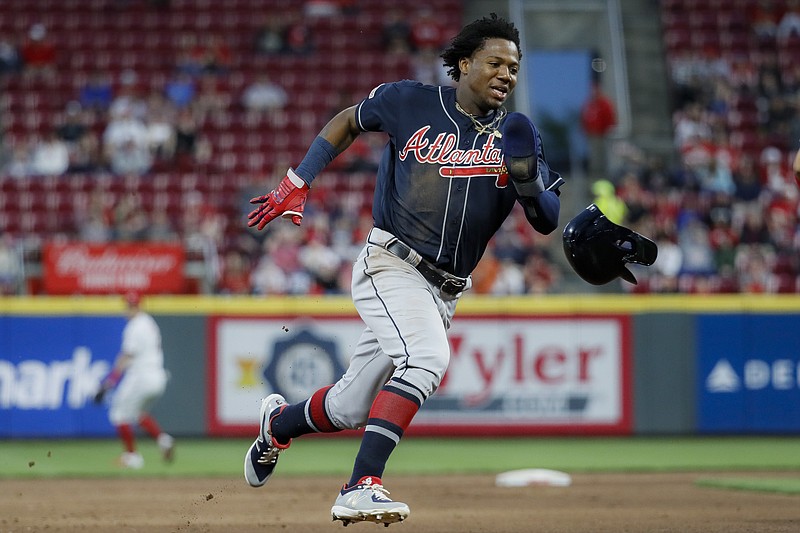 The Atlanta Braves' Ronald Acuna Jr. runs home to score on an error by Cincinnati Reds right fielder Yasiel Puig in the fifth inning of Wednesday night's game in Cincinnati.