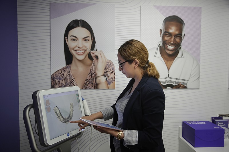 Dental assistant Jessica Buendia looks at a scanned image of patient's teeth in SmileDirectClub's SmileShop located inside a CVS store Wednesday, April 24, 2019, in Downey, Calif. CVS Health is venturing into dental care with plans to offer the relatively new teeth-straightening service. (AP Photo/Jae C. Hong)