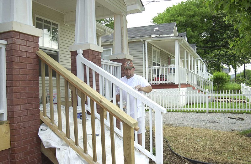 A workman paints primer on the staircase of a rebuilt home on Long Street in Southside Gardens, one of the first gentrified neighborhoods in the Southside in 2003.