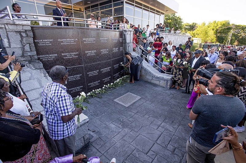 Malinda Edwards, and Mildred Betts, daughters of Willie Edwards, Jr., place roses at the new monument to those who were victims of racial terror lynchings or violence during the 1950s located at the Peace and Justice Memorial Center in Montgomery, Ala., as EJI founder and Executive Director Bryan Stevenson, top left, presides, on Monday April 29, 2019. Willie Edwards, Jr., was murdered in Montgomery in 1957. (Mickey Welsh/The Montgomery Advertiser via AP)

