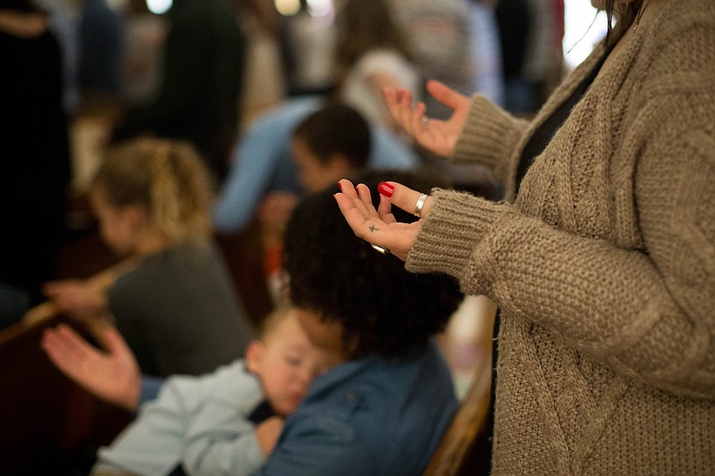 A woman raises her hands in worship during a 2016 Chattanooga area church service.