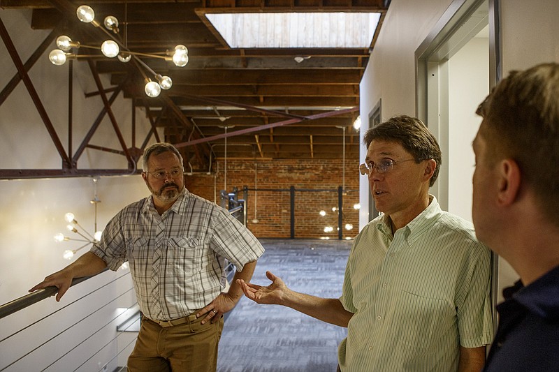 Staff photo by C.B. Schmelter / Bo Oglesby, left, and Matt McGauley, right, look on as Mike Berry talks from the mezzanine in office space at a development located at 1304 McCallie Ave. The space will include offices, a planned restaurant and possible housing.