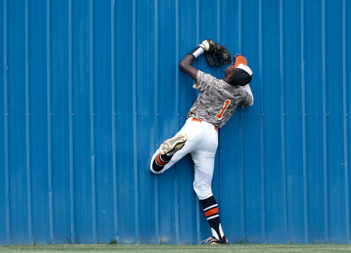 Hart County center fielder Malachi Thomas holds onto his catch as he collides with the center field wall during the continuation of the Ringgold Tigers' lightning-delayed game against Hart County at Ringgold High School on Thursday, May 2, 2019, in Ringgold, Ga.