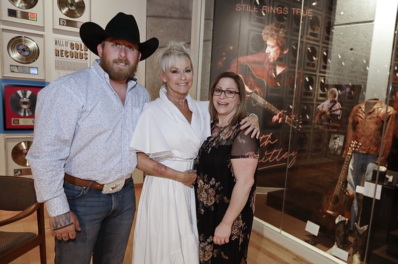 In this April 30, 2019, photo, Lorrie Morgan poses with her son, Jesse Keith Whitley, left, and adopted daughter Morgan Whitley, right, at the Keith Whitley exhibit at the Country Music Hall of Fame and Museum in Nashville, Tenn. Keith Whitley seemed destined for greatness, but his life was cut tragically short at the age of 33 because of his alcohol addiction. Morgan, his widow, said she hopes people see the struggles he endured to live his dream. Jesse Keith Whitley is the son of Lorrie Morgan and Keith Whitley, and Morgan Whitley is the daughter of Keith Whitley, adopted by Lorrie Morgan. (AP Photo/Mark Humphrey)

