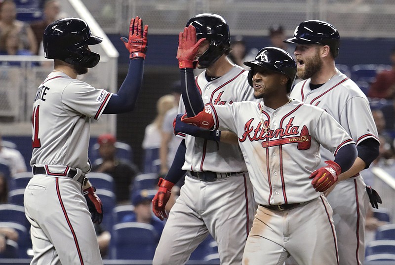 The Atlanta Braves' Ozzie Albies, right, is congratulated at the plate by Ender Inciarte, left, after hitting a grand slam during the sixth inning of Saturday's game against the host Miami Marlins. Atlanta won 9-2.